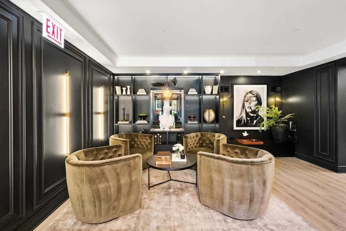 A modern lobby with a black and white color scheme, featuring a seating area with two armchairs, a coffee table, and a bookshelf with decorative items.