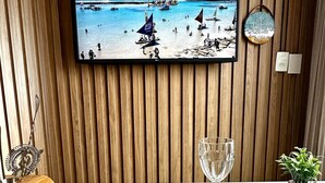 Une table à manger avec une assiette de tranches de mangue, un verre et une petite plante en pot.