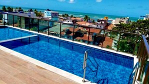Une piscine avec vue sur l’océan et des bâtiments en arrière-plan.