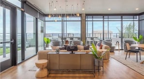 Un espacio lounge moderno con sofá, sillas, una mesa de centro y un amplio ventanal con vistas a la ciudad.