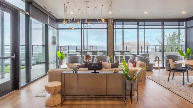 A modern lounge area with a sofa, chairs, and a coffee table. Large windows provide a view of the cityscape. - Boulevard Stays Modern Highrise STU Sky Pool, Gym 09 (Phoenix)