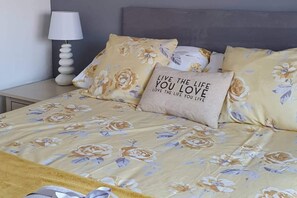 A bed with floral bedding and a motivational pillow. - Seaview-petsok-patio-1br (St Austell)