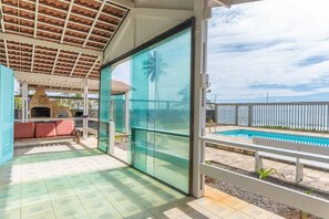 Un espace extérieur abrité comprenant une piscine, un barbecue et un coin salon offrant une vue sur l’océan.
