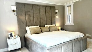 Ein modernes Schlafzimmer mit einem großen Bett, einem Nachttisch und einem Beistelltisch.