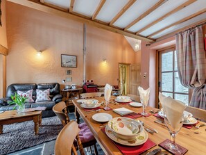 Un'accogliente sala da pranzo con un tavolo in legno apparecchiato per un pasto, un divano in pelle e un caminetto.