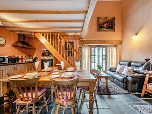 A cozy living room with a fireplace, a dining area with wooden furniture, and a staircase leading to an upper level.