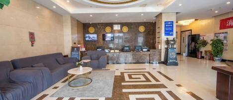 Un hall de hotel con mostrador de recepción, zona de estar y un diseño decorativo en el suelo.
