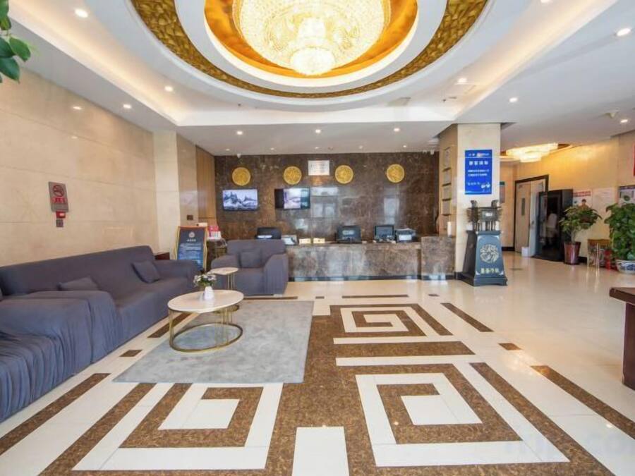 A hotel lobby with a reception desk, seating area, and a decorative floor pattern.