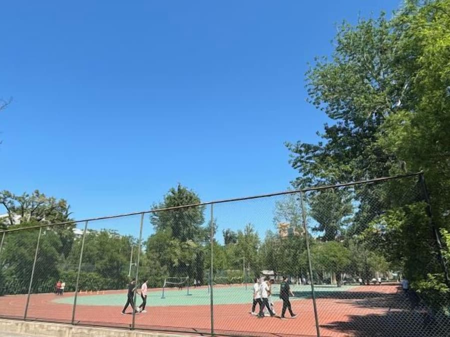 An outdoor tennis court surrounded by trees.