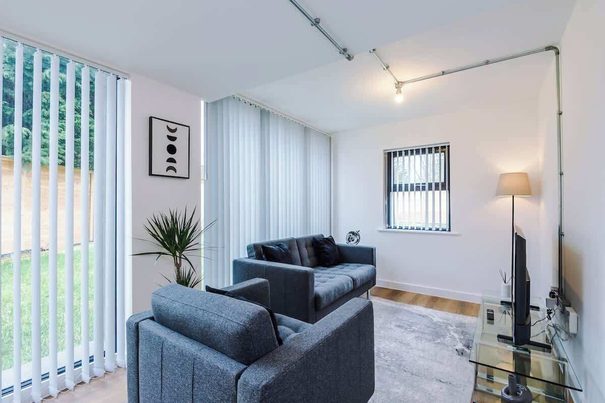 A modern living room with a sofa, a glass coffee table, a TV, and a lamp.