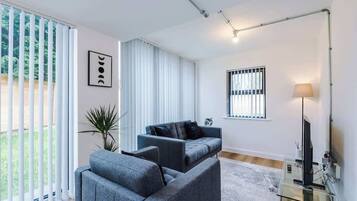 A modern living room with a sofa, a glass coffee table, a TV, and a lamp.