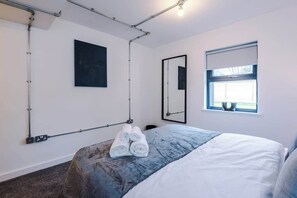 Une chambre d’hôtel avec un lit, une fenêtre donnant sur un paysage agréable, un miroir fixé au mur et un tableau.