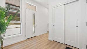 En hall med trägolv, vita väggar och en krukväxt.