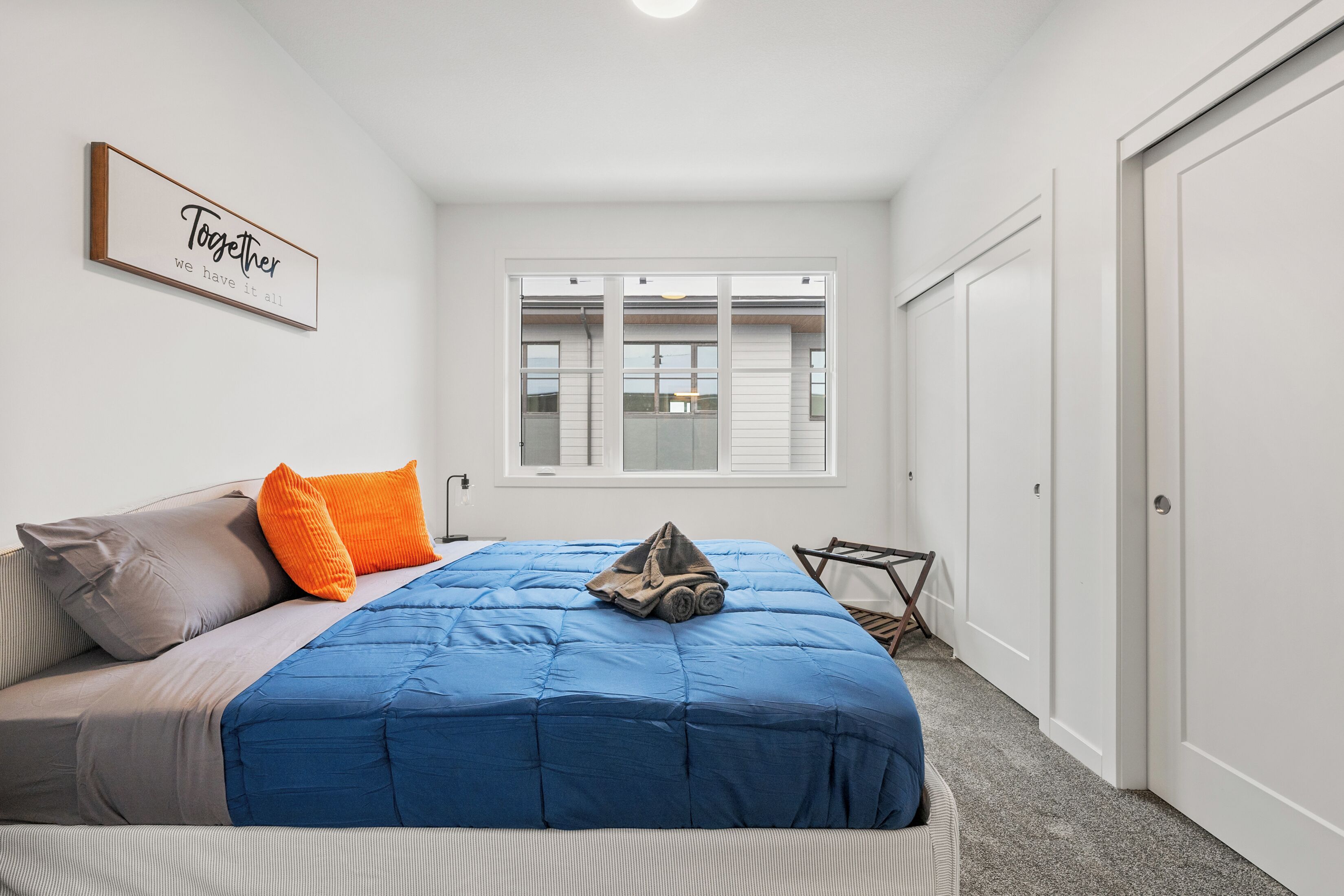 Un dormitorio con cama, almohadas, una ventana y una puerta.