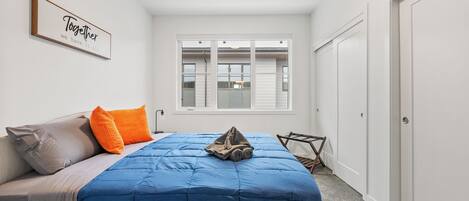 Un dormitorio con cama, almohadas, una ventana y una puerta.
