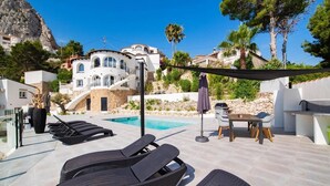 Un espace aménagé au bord de la piscine, avec des chaises longues, une table et un barbecue.
