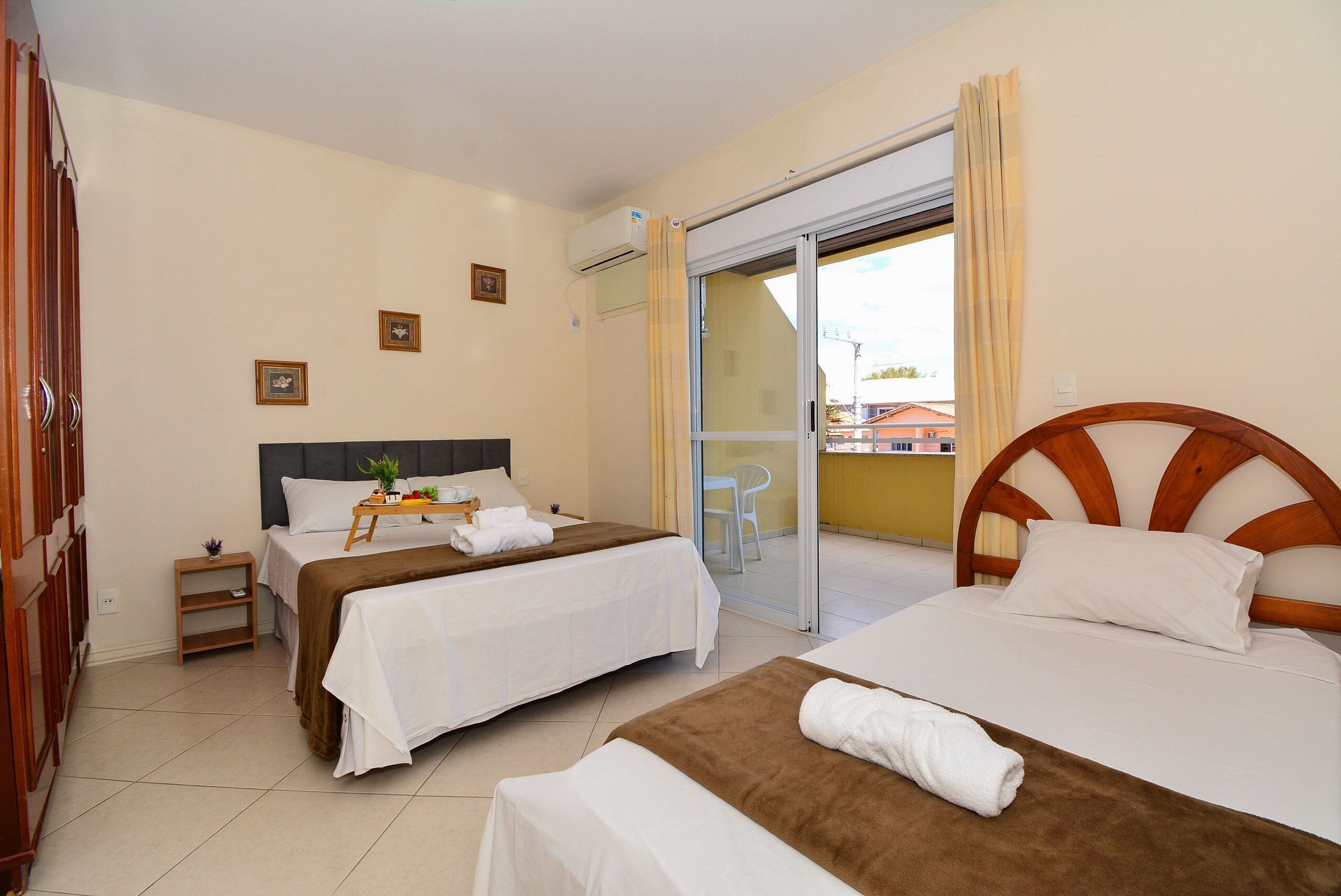 A hotel room with two beds, a balcony, and a sliding glass door.