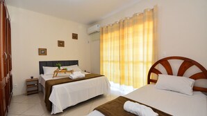 Une chambre d’hôtel avec deux lits, une tête de lit en bois, une table de chevet avec une lampe et une fenêtre avec des rideaux.