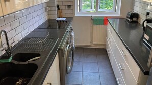 A modern kitchen with a built-in oven, a sink, and a window with a view of greenery. - London Apartment - Sleeps 3-city Escape- Balcony (London)