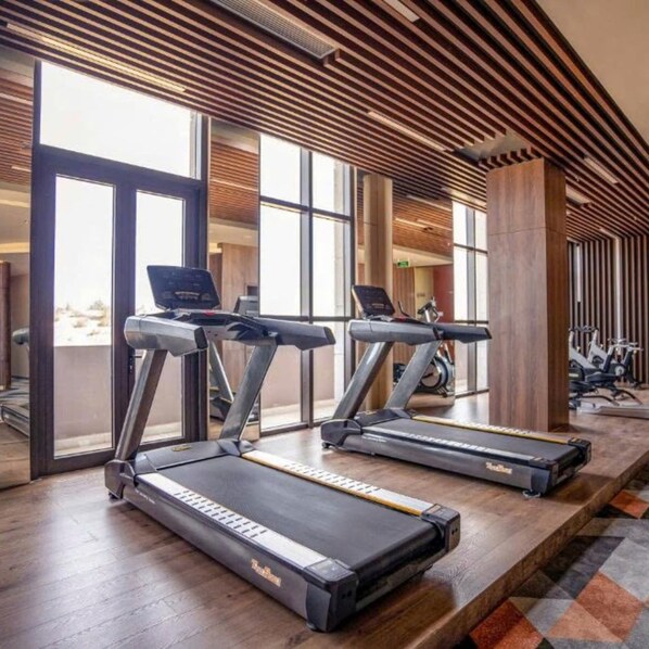 A gym with treadmills, large windows, and a wooden ceiling. - Mandala Nearly Beach - Condotel Apec Mui Ne (Mui Ne)