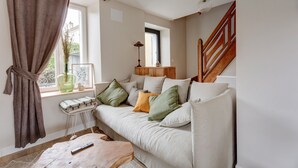 Un salon avec un canapé, une table basse, une lampe et une fenêtre avec des rideaux.