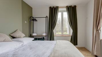 Une chambre à coucher avec un lit, une table de chevet, une fenêtre avec des rideaux et un radiateur.
