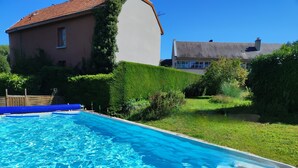 Une piscine rectangulaire à l’eau d’un bleu limpide, entourée d’une pelouse et d’une clôture en bois.