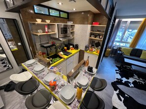 Une cuisine moderne avec un coin repas, équipée d’un four à micro-ondes, d’un four et de divers ustensiles de cuisine.