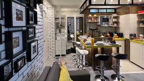 Une cuisine moderne avec des tabourets de bar, une table à manger et un mur décoratif en briques.