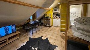 Een gezellige, compacte leefruimte met een eethoek, een kitchenette en een televisie.