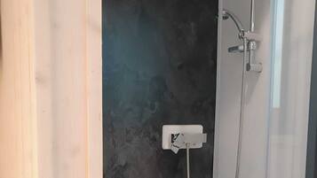 A modern shower with a glass enclosure, a dark textured wall, and a white base.