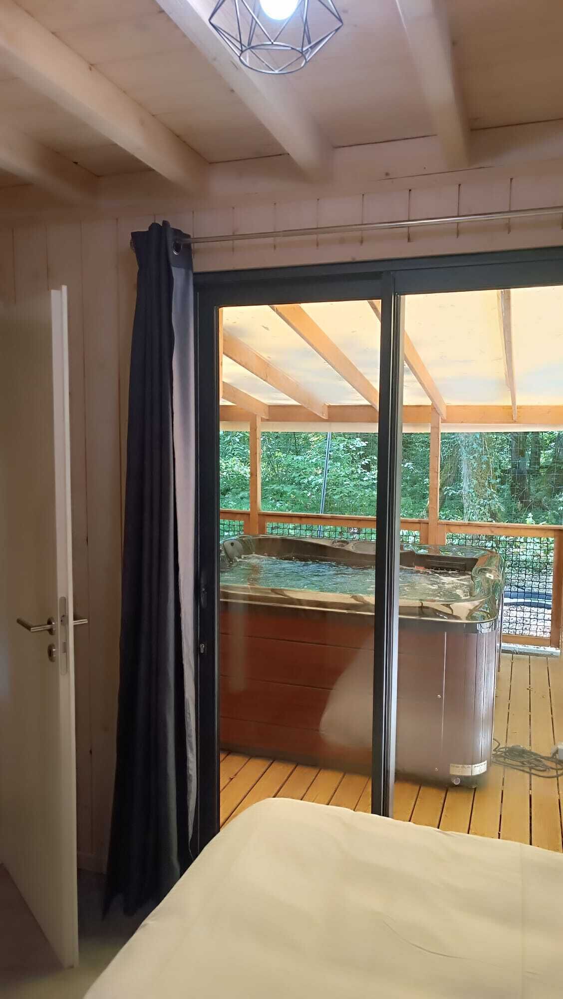 Une pièce dotée d’une grande porte-fenêtre coulissante donnant accès à un espace extérieur avec un jacuzzi.