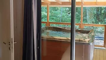 Une pièce dotée d’une grande porte-fenêtre coulissante donnant accès à un espace extérieur avec un jacuzzi.