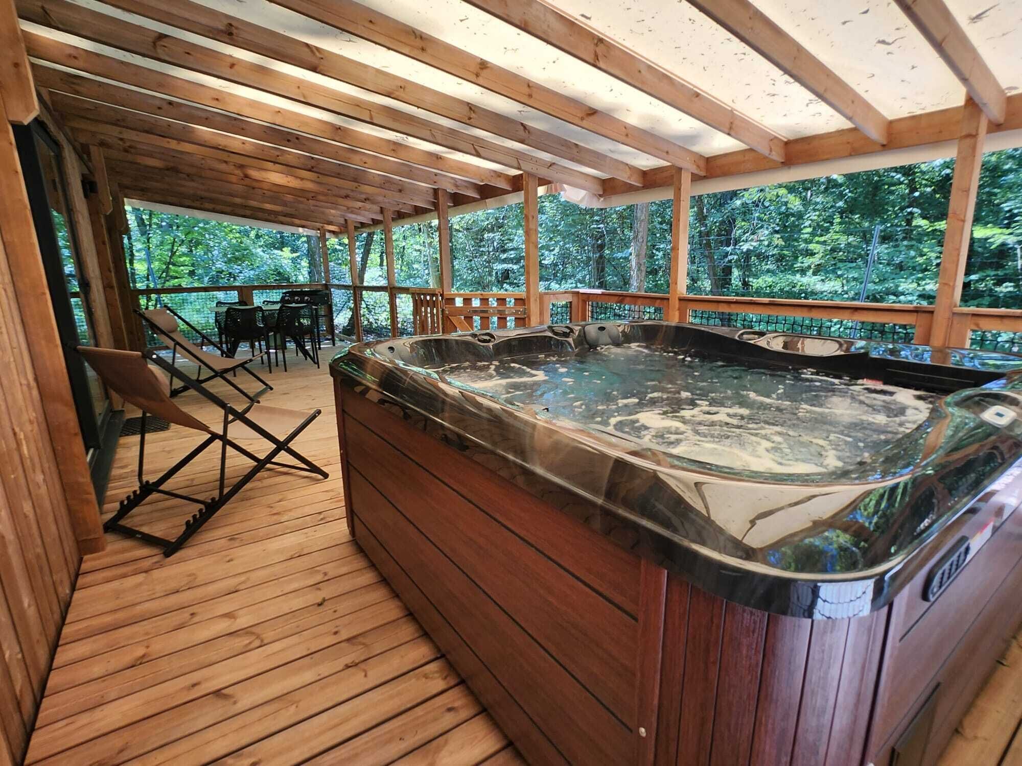 Une terrasse en bois avec un jacuzzi et du mobilier d’extérieur.