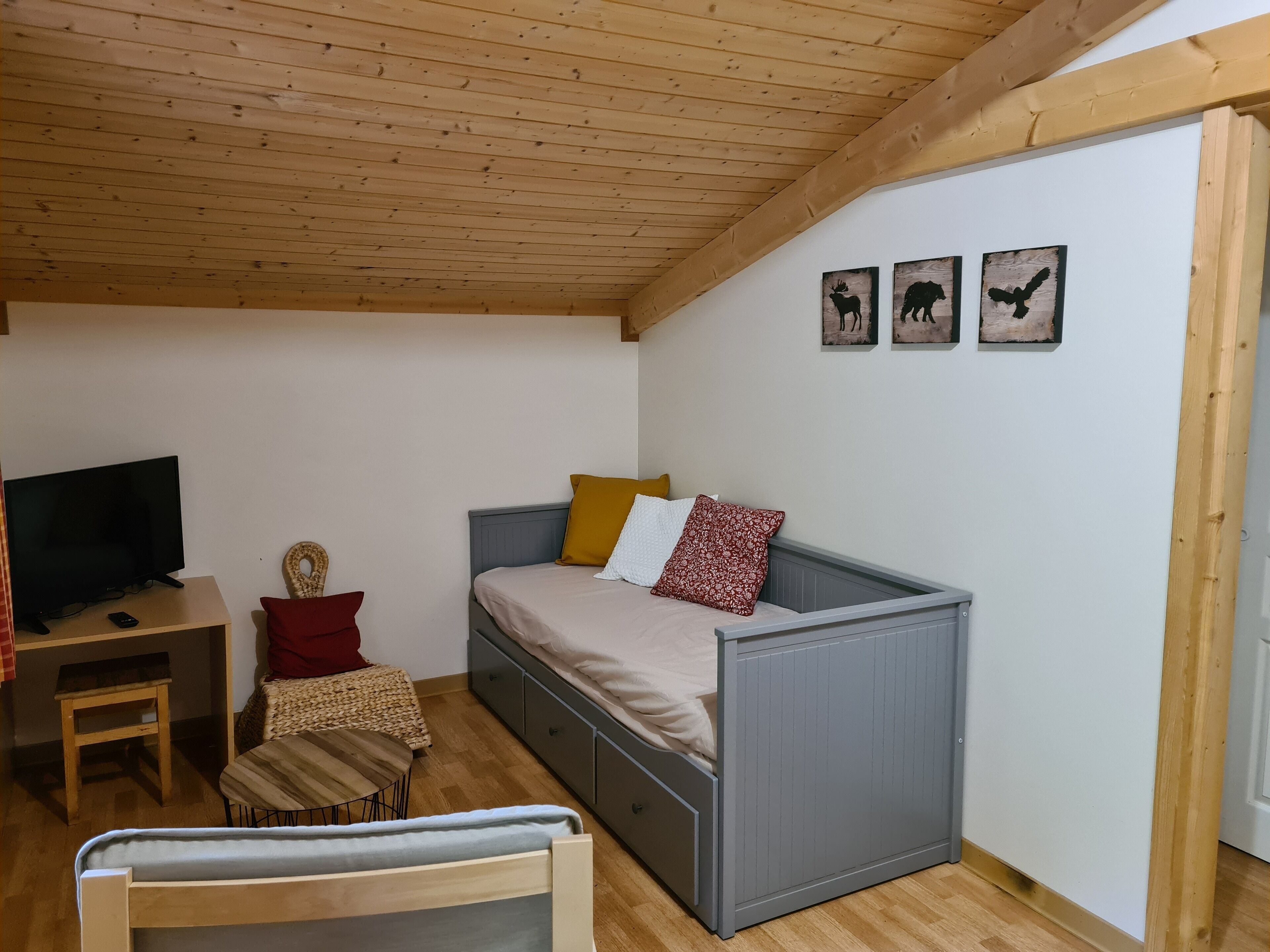 A small, cozy bedroom with a single bed, a television, a small table, and a chair.