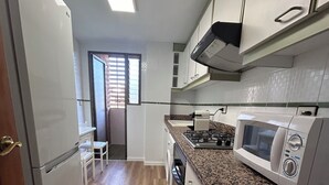 A kitchen with a refrigerator, microwave, stove, and cabinets.
