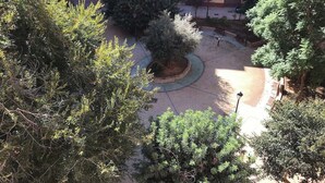 An outdoor courtyard with a central circular area, surrounded by trees and benches.