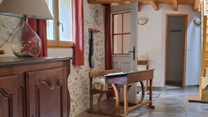 A room with a wooden cabinet, a table with a box of children's toys, a lamp, and a window with red curtains. - Gîte à la ferme de Palauqui, ideal for family vacations (Montjardin)