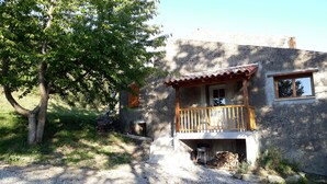 A rustic house with a wooden balcony, a stone exterior, and a gravel driveway. - Gîte à la ferme de Palauqui, ideal for family vacations (Montjardin)