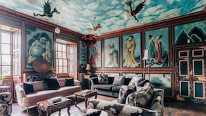 Une pièce décorée dans un style traditionnel, comprenant un canapé, des fauteuils et un pouf à motifs.