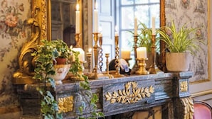 Une console en marbre agrémentée de détails dorés et d’un papier peint à motifs floraux.