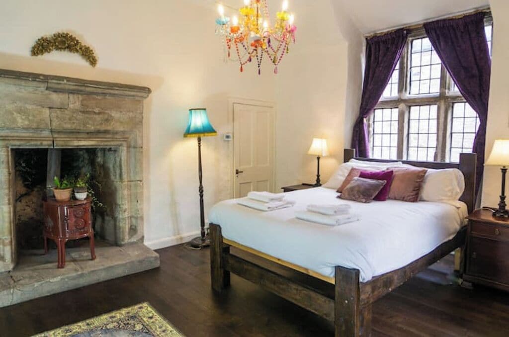 A bedroom with a large bed, a fireplace, and a window with curtains.