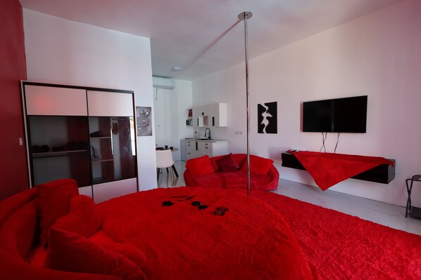 A modern bedroom with a large bed, a wardrobe, a TV, and a red sofa. - PÀRIS Villas Honeymoon Suite (Gros Islet)