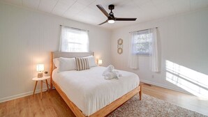 A spacious bedroom with a large bed, a ceiling fan, and two bedside tables with lamps. - Cozy Riverside Cottage—Quiet—3-Beds—Fully Updated! (Belmont)
