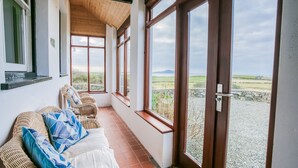 En balkong med möbler i rotting, utsikt över landskapet och en mur av sten.