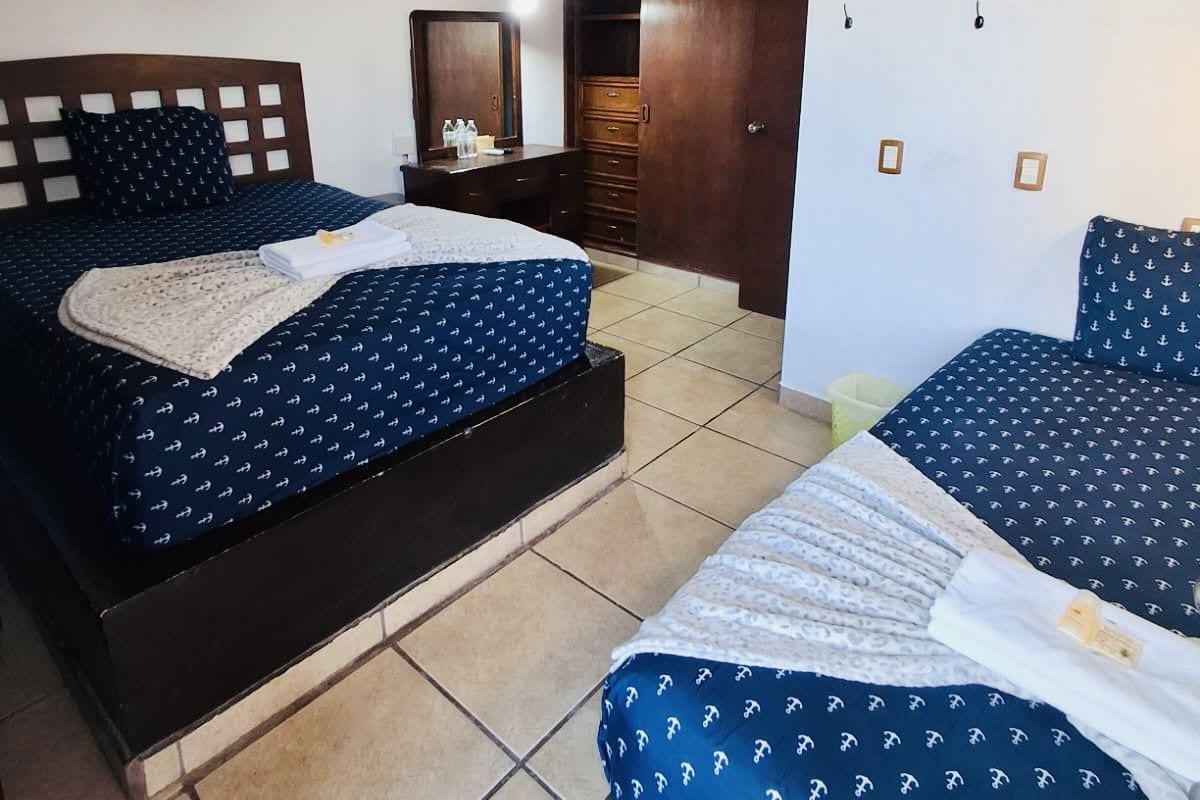 Un dormitorio con dos camas, un ventilador de techo, un armario y un espejo.
