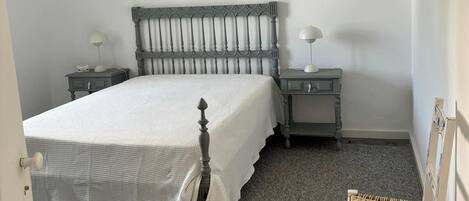 Ein Schlafzimmer mit einem Bett, zwei Nachttischen, einem Sessel und einer Pendelleuchte.
