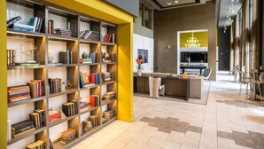 A modern library with bookshelves, a seating area, and a kitchen/lounge in the background. - Quiet Comfort & Urban Style: 2-Bedroom Condo 31 (Birmingham)