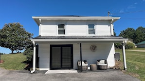 A two-story house with a front porch, a black garage door, and a wreath on the wall. - Retro Retreat! 2BR, 1 Bath Home with WiFi, AC in wonderful Bristol, VA (Bristol)