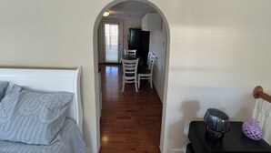 A narrow hallway leading to a dining area with a table and chairs, a kitchen with cabinets, and a bed with a patterned blanket. - Retro Retreat! 2BR, 1 Bath Home with WiFi, AC in wonderful Bristol, VA (Bristol)